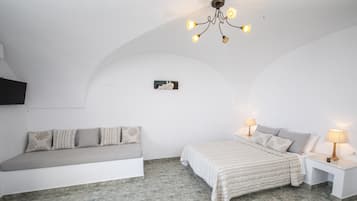 A bedroom with a bed, bedside tables, a bench, a chandelier, and a wall-mounted TV.