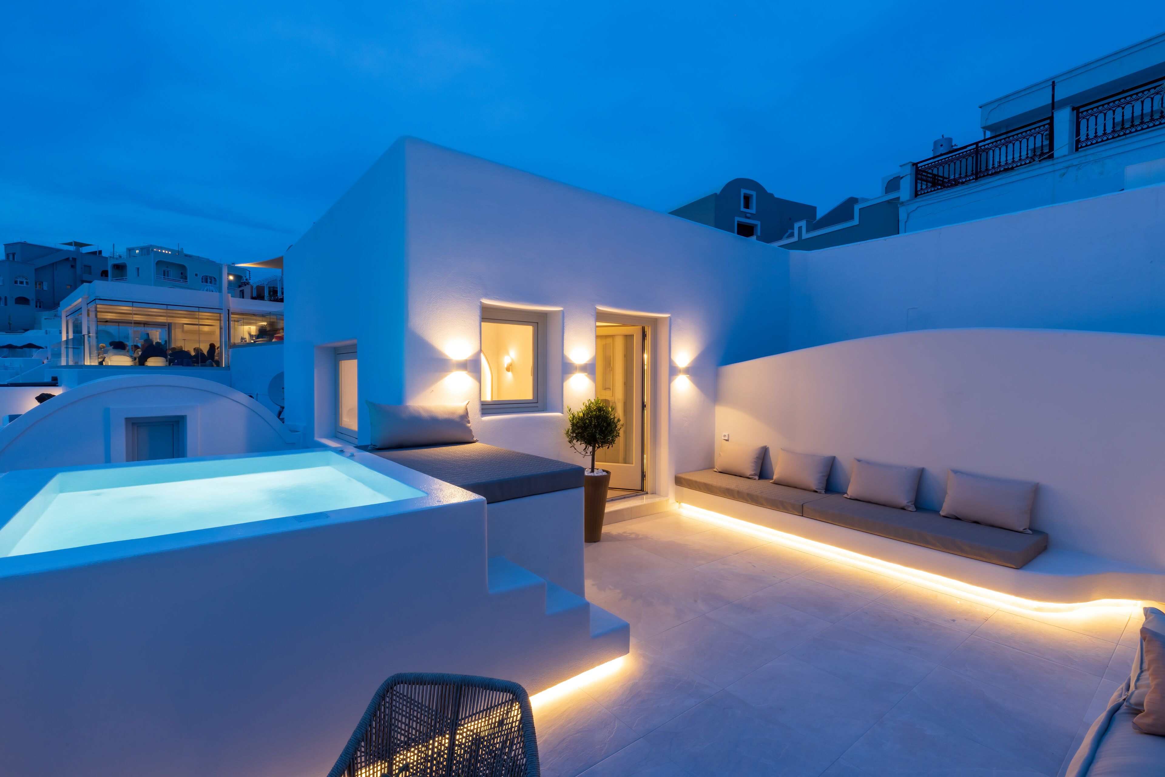 Un espace de vie extérieur moderne doté d’une piscine, de coins salon et d’un escalier menant à un niveau supérieur.