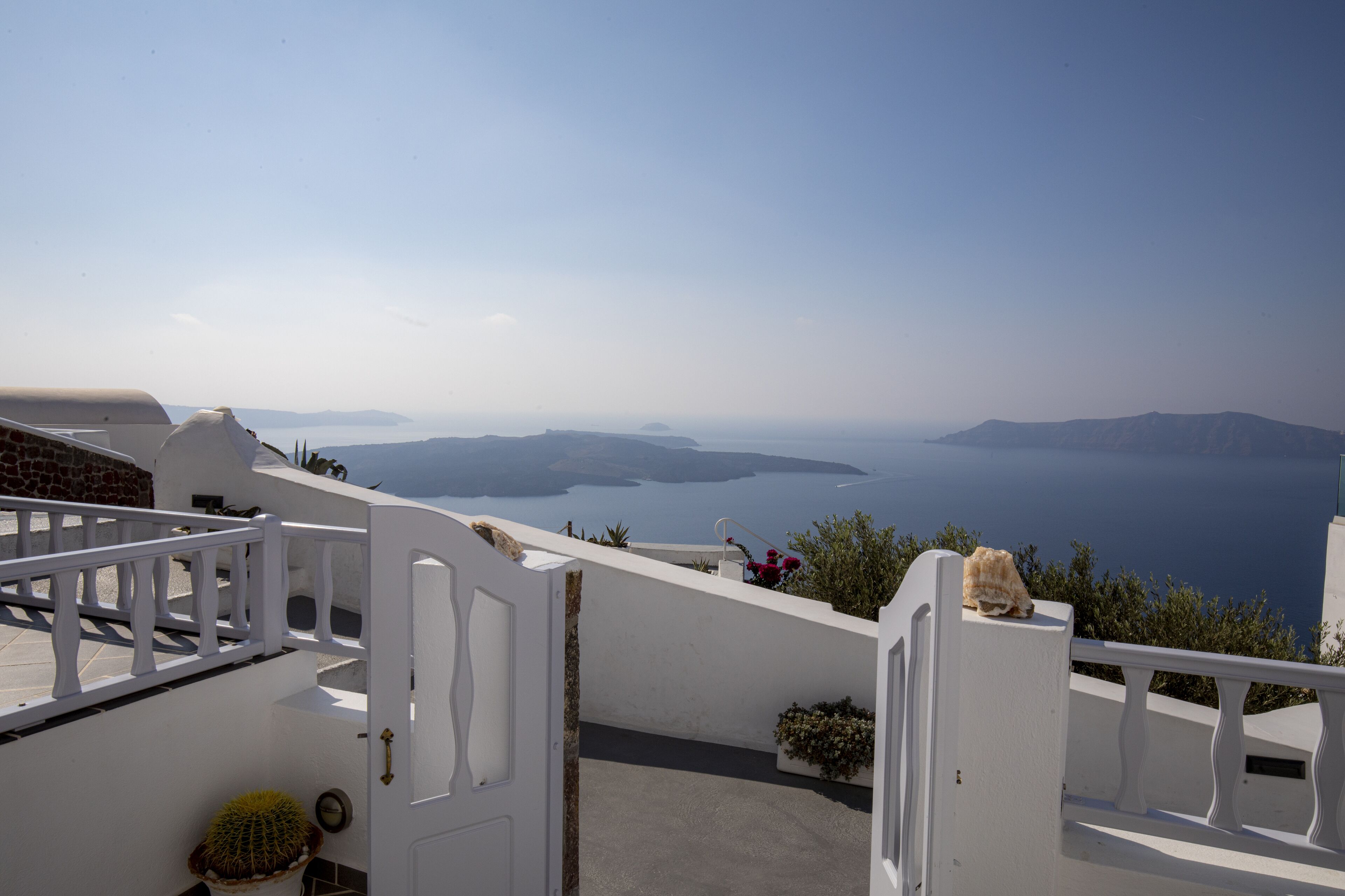 A white-walled building with a balcony overlooking a coastal landscape.