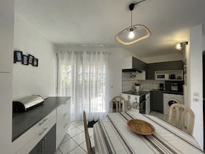 A compact kitchen with a dining area, a microwave, a stove, and a washing machine.