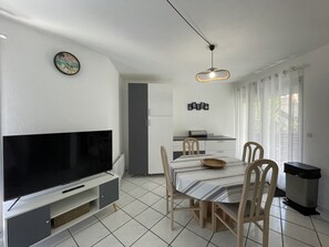 A modern kitchen with a dining table, chairs, and a TV.