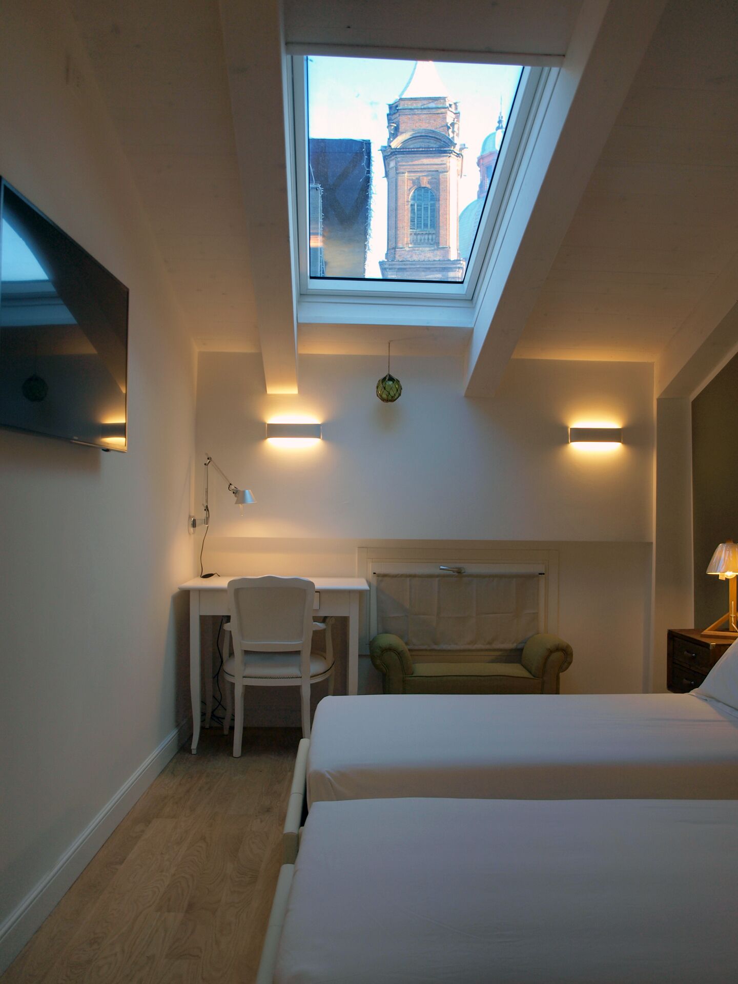 Un dormitorio con tragaluz, un escritorio, una silla y una cama.