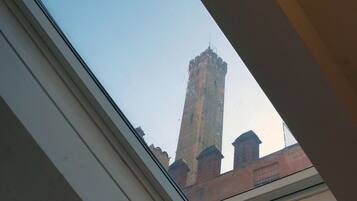 A skylight window with a view of a tall, historic building with a pointed roof and a chimney.