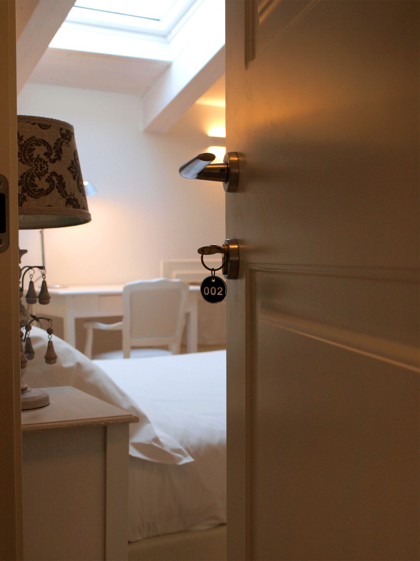 Una camera d'albergo con un letto, una scrivania e una lampada.