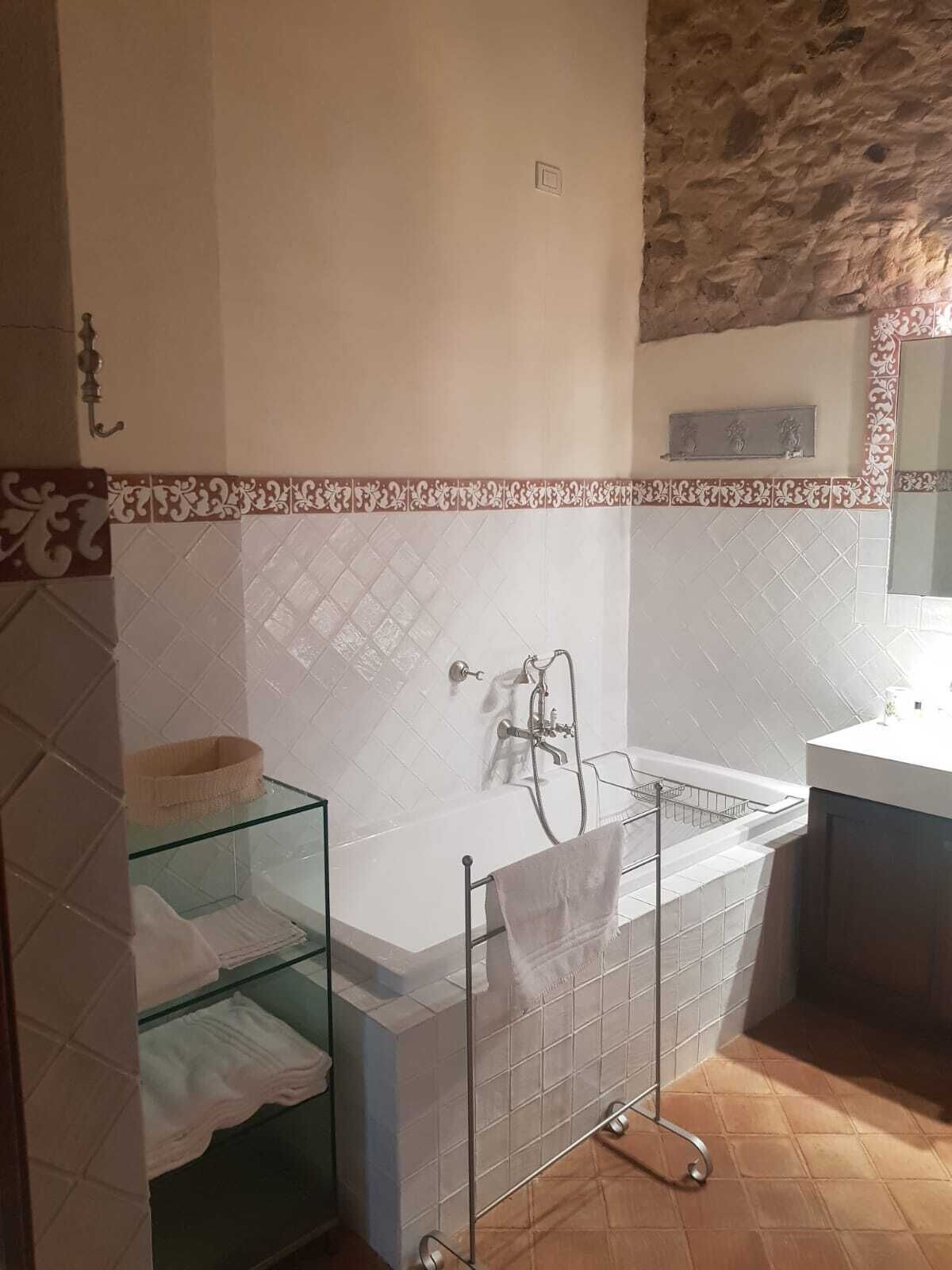 A bathroom with a bathtub, a glass shelf, and a towel rack.