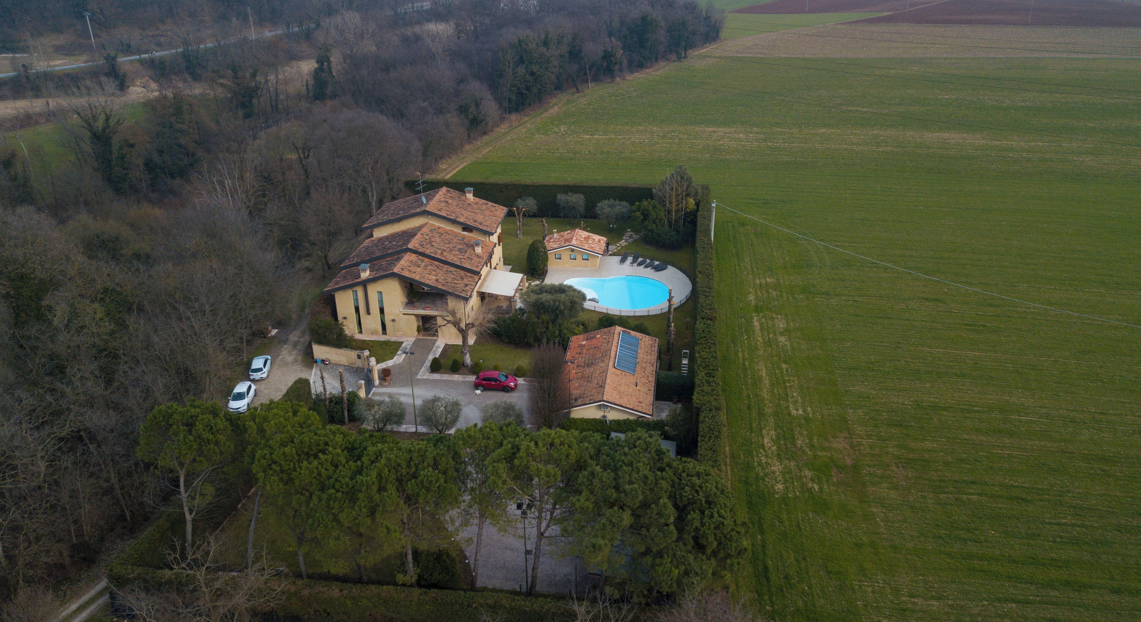 Vista aérea de una propiedad residencial con piscina, varios automóviles y abundante vegetación.
