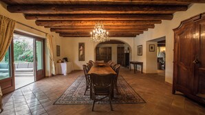 A dining room with a wooden ceiling, chandelier, and a large dining table surrounded by chairs.