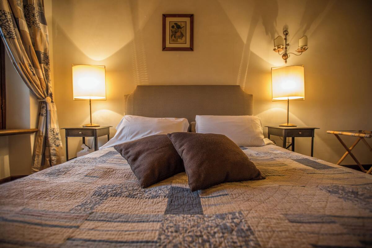 A neatly made bed with a quilt, two pillows, and two bedside lamps.