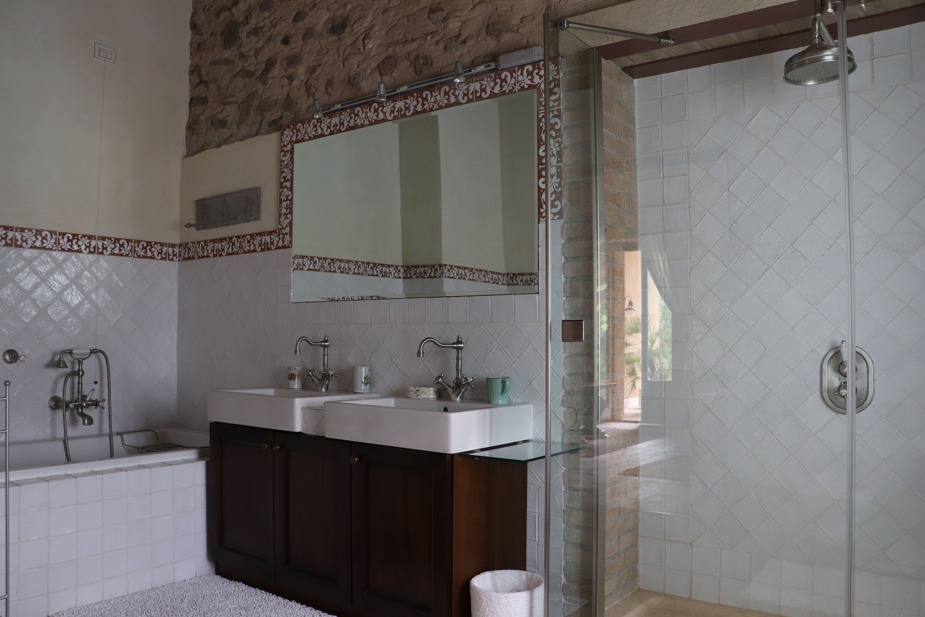 A modern bathroom with a glass shower enclosure, a double sink vanity, and a large mirror above the sink.