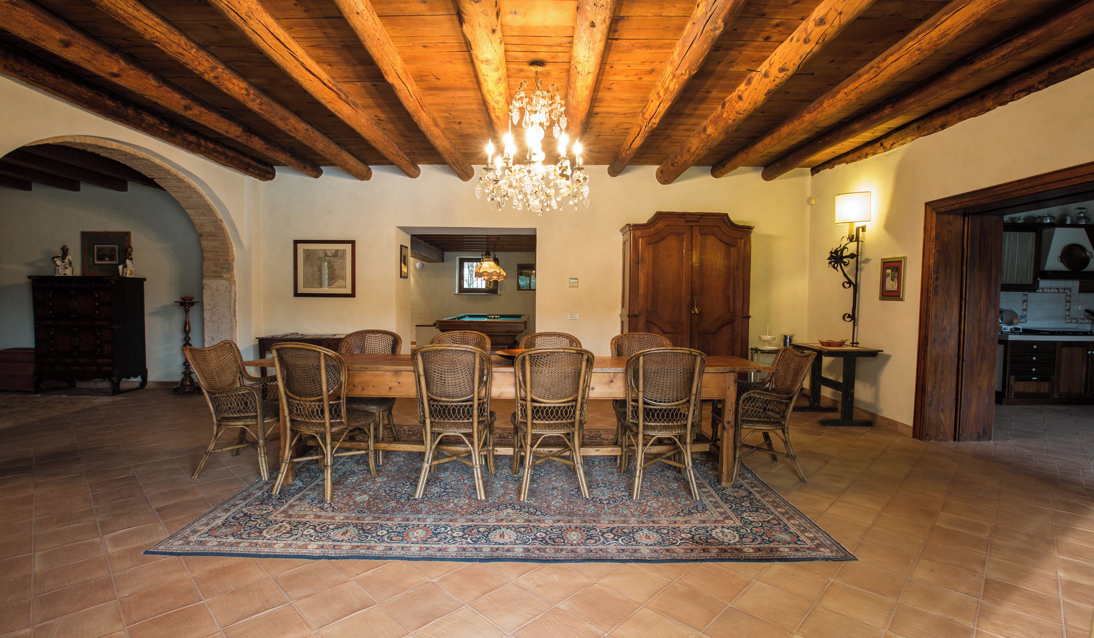 A dining area with a wooden table, wicker chairs, and a chandelier.