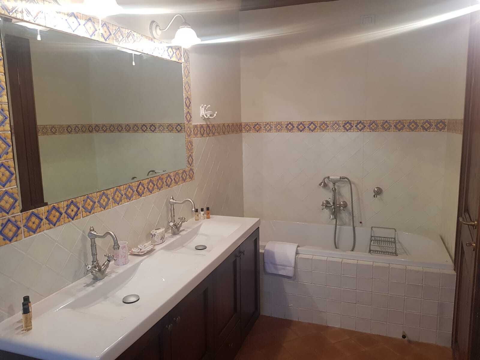 Une salle de bain avec deux lavabos, un grand miroir, une douche et des murs recouverts de carreaux à motifs.