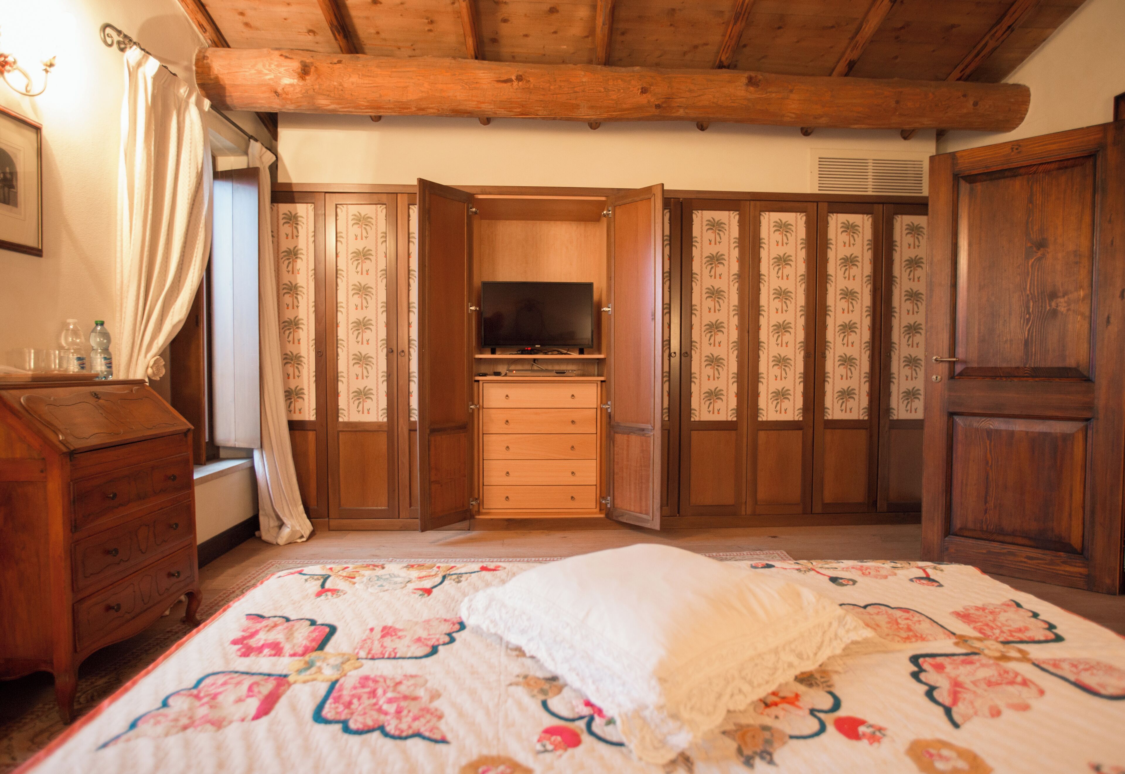 A bedroom with a bed, a dresser, a television, and a wardrobe.