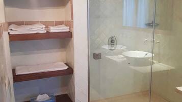 A bathroom with a glass-enclosed shower, a toilet, and a sink.