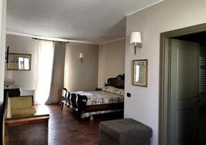 A bedroom with a bed, a chair, a bedside table, and a lamp. - Agriturismo Bassanine (Monticelli d'Ongina)