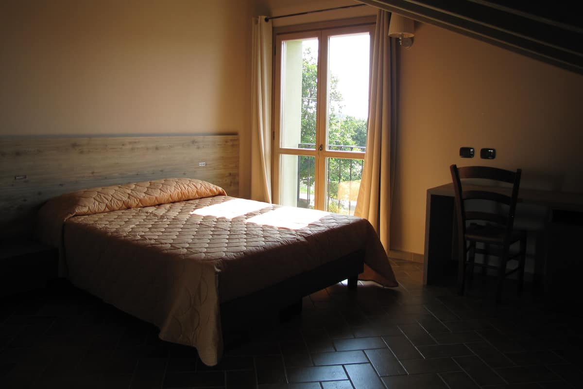 A bedroom with a bed, a chair, and a window.
