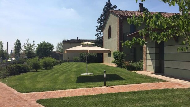 Un césped cuidado con un patio, un área de estar cubierta y un edificio con techo de tejas.
