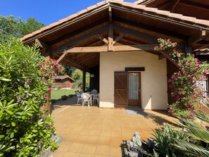 Ein überdachter Patio-Bereich mit Holzboden, einer Tür und einem kleinen Tisch mit Stühlen.