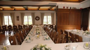 Ein langer Esstisch, festlich gedeckt für eine Veranstaltung, mit Stühlen, weißen Tischdecken und floralen Mittelpunkten.