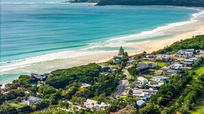 A coastal residential area with houses, a beach, and a clear view of the ocean.