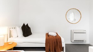 Ein Hotelzimmer mit einem Bett, einem Nachttisch mit Lampe, einer Wandklimaanlage und einem Spiegel.