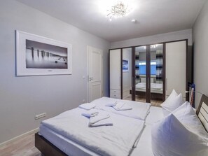 Habitació d'hotel amb llit, armari, mirall i quadre al mur.