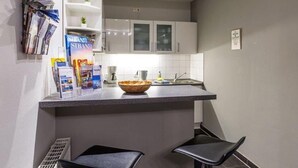 A compact kitchen with a central island, white cabinetry, and a small seating area. - (204) 2-room apartment - Apartment house Villa Laura (Kühlungsborn)