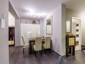 Quarto moderno com área de jantar, guarda-roupa e espelho.