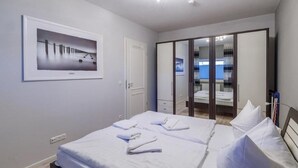 A hotel room with a bed, a wardrobe, a mirror, and a framed picture on the wall. - (204) 2-room apartment - Apartment house Villa Laura (Kühlungsborn)