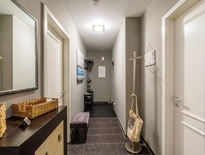 A narrow hallway with a dark wooden bench, a wall-mounted basket, and a coat rack with a bag. - (204) 2-room apartment - Apartment house Villa Laura (Kühlungsborn)