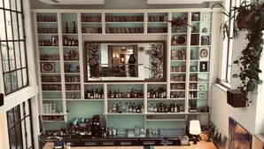A bar area with a long counter, multiple stools, and shelves filled with bottles and glasses. - Hotel Amour Nice (Nice)