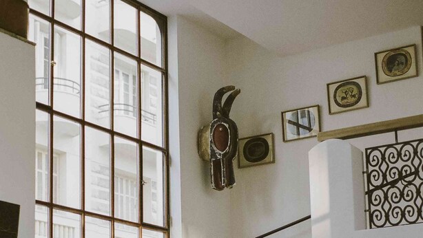 A dining area with a staircase, arched windows, and a decorative wall piece. - Hotel Amour Nice (Nice)