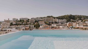 A rooftop pool with a view of a cityscape and a hill in the background. - Hotel Amour Nice (Nice)
