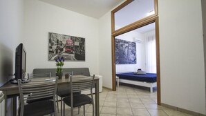 Ein kleines Zimmer mit Essbereich, einem Bett und einem großen Fenster.