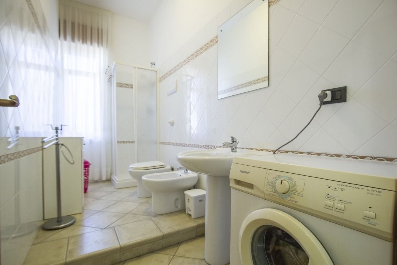 A bathroom with a washing machine, a sink, a toilet, and a bidet.