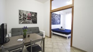 Ein kompakter Wohnbereich mit Essplatz, einer Couch und einem Bett.