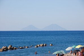 A beach with large rocks in the water, people swimming, and umbrellas on the sand. - Perla - cozy 2 bedroom apartment centrally located in Capo d'Orlando, Sicily (Capo d'Orlando)
