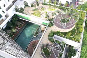 Enjoy the serene rooftop garden with a swimming pool and wooden deck, surrounded by lush greenery and trees.