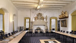 A formal meeting room with long tables, chairs, and a decorative fireplace. - Burghotel Schnellenberg (Attendorn)