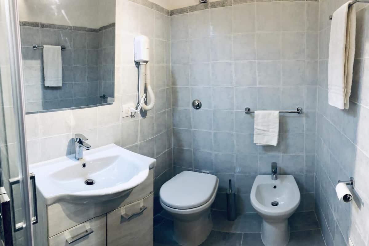 Een kleine badkamer met een wastafel, toilet, bidet en handdoekhouder.