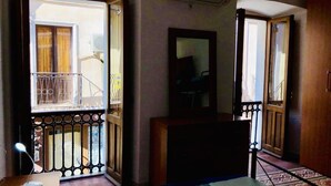 A hotel room with a bed, a desk, a chair, a mirror, and a balcony with a metal railing. - Il Terrazzino (Iglesias)