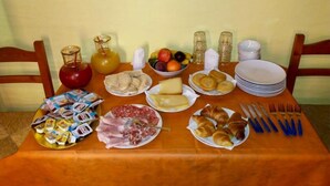 A breakfast table with various food items, plates, and utensils. - Il Terrazzino (Iglesias)