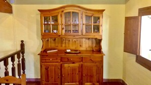 A wooden cabinet with glass doors, a wooden countertop, and a wooden chair. - Il Terrazzino (Iglesias)