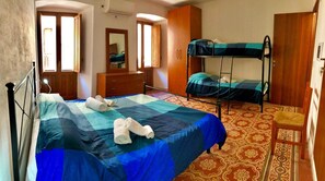 Una habitación con una cama litera, una cama individual, un armario de madera, un aparador y una alfombra estampada.