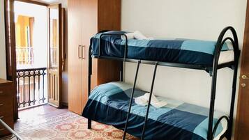 Un letto a castello con copriletto azzurro e bianco a righe, un armadio in legno e un pavimento decorato.