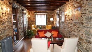 A cozy living room with stone walls, a fireplace, and a comfortable seating area with a coffee table. - Casa Rural Vila Pomar (Ribadeo)