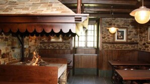 A rustic interior with stone walls, wooden benches, and a fireplace. - Casa Rural Vila Pomar (Ribadeo)