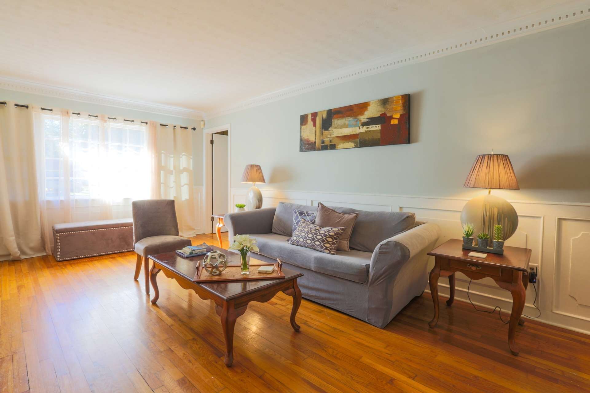 A living room with a grey sofa, two armchairs, a coffee table, and a side table with a lamp.