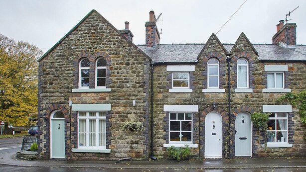 A stone building with multiple windows and doors, featuring a traditional architectural style with a steeply pitched roof. - Rosella Cottage (Pickering)
