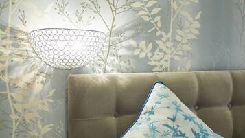 A room with a tufted headboard, a patterned wall, and a hanging light fixture.