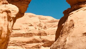 A natural rock formation with two people standing on top. - Wadi Rum Desert Camp (Wadi Rum)
